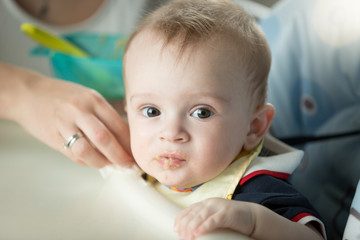 Portrait of cute baby boy sitting in highchair and looking at camera