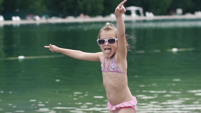 little girl fooling around and makes funny faces. the child bathing in the lake and enjoys a hot summer day. Slow motion