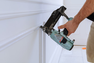 Carpenter using a brad nail gun to complete framing trim