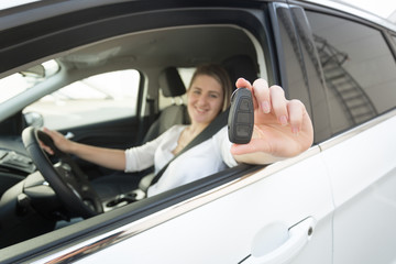 Closeup of female driver showing keys through open window of car