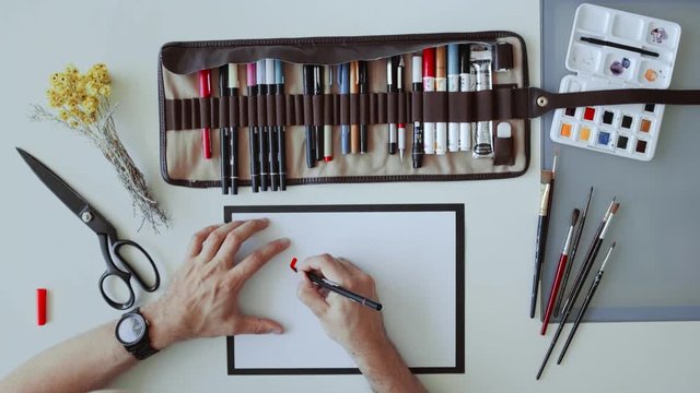 Top view on calligraph artist writing word Future with red watercolor marker on white a4 shet of paper surrounded by designer tools