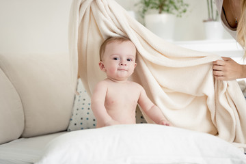 Fototapeta na wymiar Mother covering her baby boy in big white blanket on bed