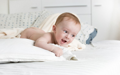 Adorable baby boy crawling on big bed at bedroom