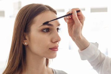 Portrait of a beautiful model during an eyebrow correction procedure. Woman correcting eyebrows form