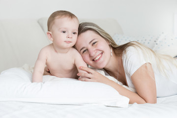Happy smiling baby boy and mother lying on pillow and looking at camera