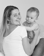 Black and white portrait of young mother kissing and playing with her 9 months old baby boy
