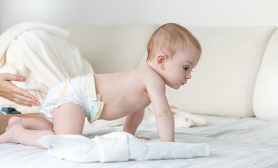 9 months old baby in diapers crawling on bed