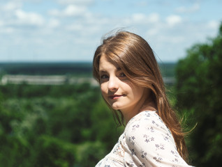 Fototapeta premium girl portrait in three quarters. beautiful girl sitting on a bench in the Park and looking at camera closeup
