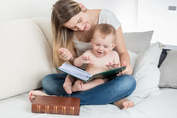 Happy smiling mother looking at photo album with her baby boy
