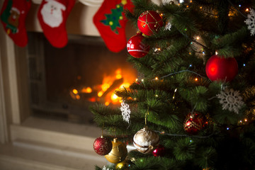 Fototapeta na wymiar Background of Christmas tree at living room with burning fireplace decorated with traditional stockings for gifts
