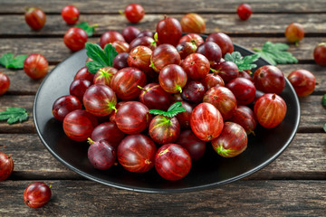 Fresh Juicy gooseberry in a black plate on wooden rustic table