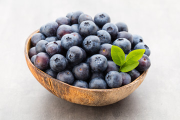 Fresh blueberries natural coconut in a bowl on a gray background.