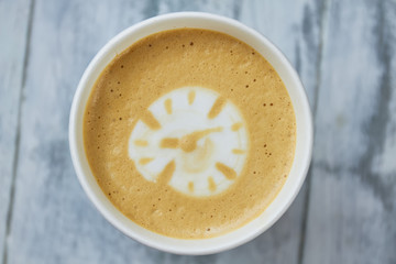 Latte art clock. Light coffee foam, top view. Does coffee boost productivity.