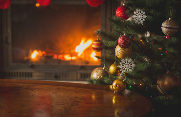 Closeup image of baubles on Christmas tree in front of burning fireplace. Beautiful Christmas...