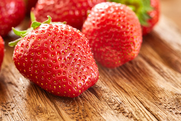 Close-up of the fresh red strawberries on the brown wooden table.