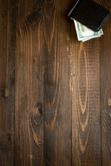 Money in leather purse on wooden background
