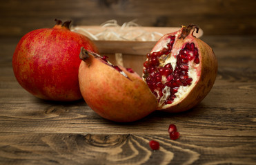 Closeup image of pomegranates and basket lying on old wooden desk