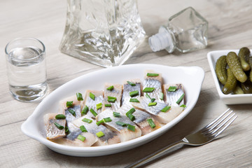 Pieces of herring with onions, gherkins and vodka. Selective focus