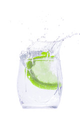 Green citrus drops into a glass with a drink