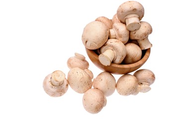 White mushrooms champignons lie in a wooden cup, isolated on a white background
