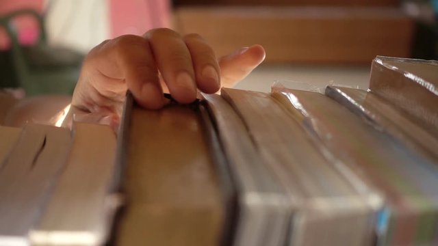 Slow motion of woman hand finding a book on bookshelf in the library
