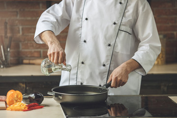  Mature man professional chef cooking meal indoors