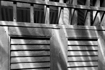 Closeup on rustic old wooden window detail with ventilation void above in black and white.
