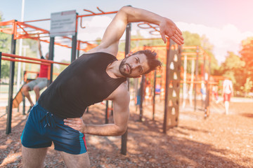 Man doing arms exercise. Industrial workout. Warming before sport. Portrait of strong guy doing muscles exercises on training apparatus outdoors, fit pumps biceps at seashore horizontal bar, sportsman