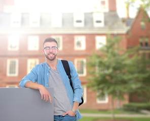 Portrait of a smiling male student holding blank board standing on the street