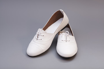 Pair of womans white shoes isolated on gray background
