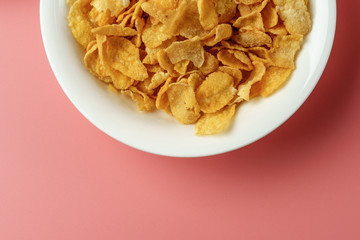 Corn flakes and yogurt in white bowl  place on pink background