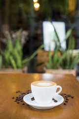 Coffee cup and coffee beans on table on a wooden desk