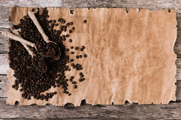 Coffee beans and wooden spoons on an old sheet of paper