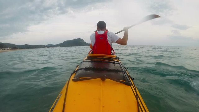 Rear view of man paddling the kayak at sea