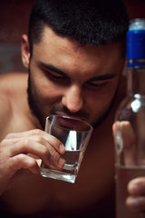 Young drunken man with bottle and glass