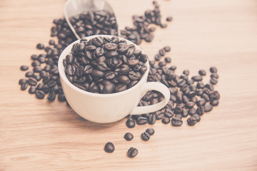 Fototapeta na wymiar Coffee beans and cup on wooden background, warm tone