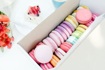 Macaron dessert and tasty fruit cake on white wooden table