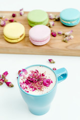 View on morning french macarons and a blue cappuccino cup with rose petals