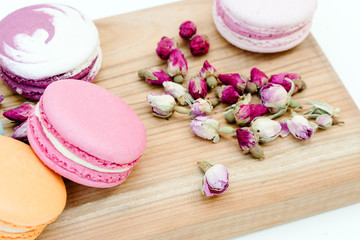 French delicious pink color macarons cookies and small roses on wood desk.