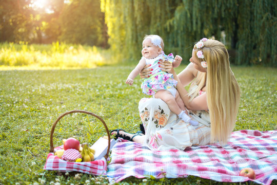 Mother and daughter enjoying picnic together in the park.