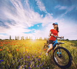 woman riding a bicycle on a blooming poppy meadow