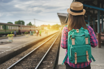Traveler woman walking and waits train on railway platform, Sun light flare, Selective focus