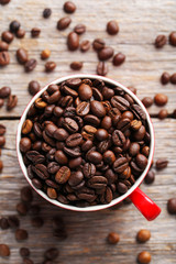 Roasted coffee beans in cup on a grey wooden table