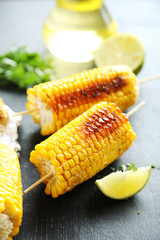 Tasty grilled corn on black wooden table