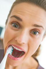 Funny portrait of young woman intensively brushing teeth