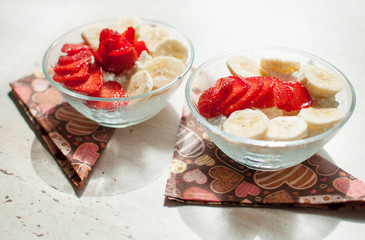 Two bowls of curd with strawberry and banana.