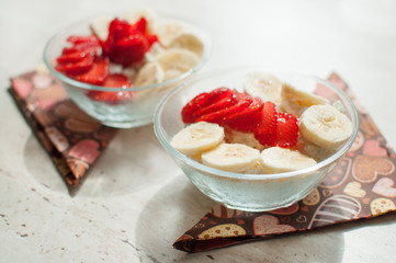 Two bowls of curd with strawberry and banana.