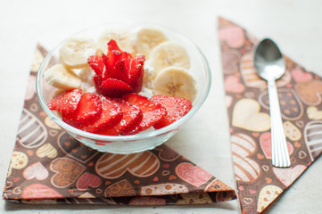 Two bowls of curd with strawberry and banana.