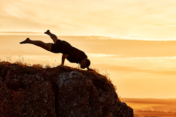 Silhouette of man doing yoga meditation against beautiful sky with clouds.