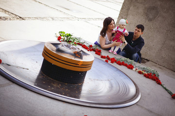 A young family with a baby at the monument of the eternal flame